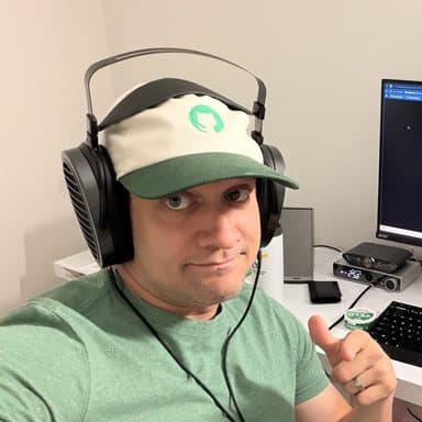 Vin Falkiewicz at his desk, headphones on, giving a thumbs-up